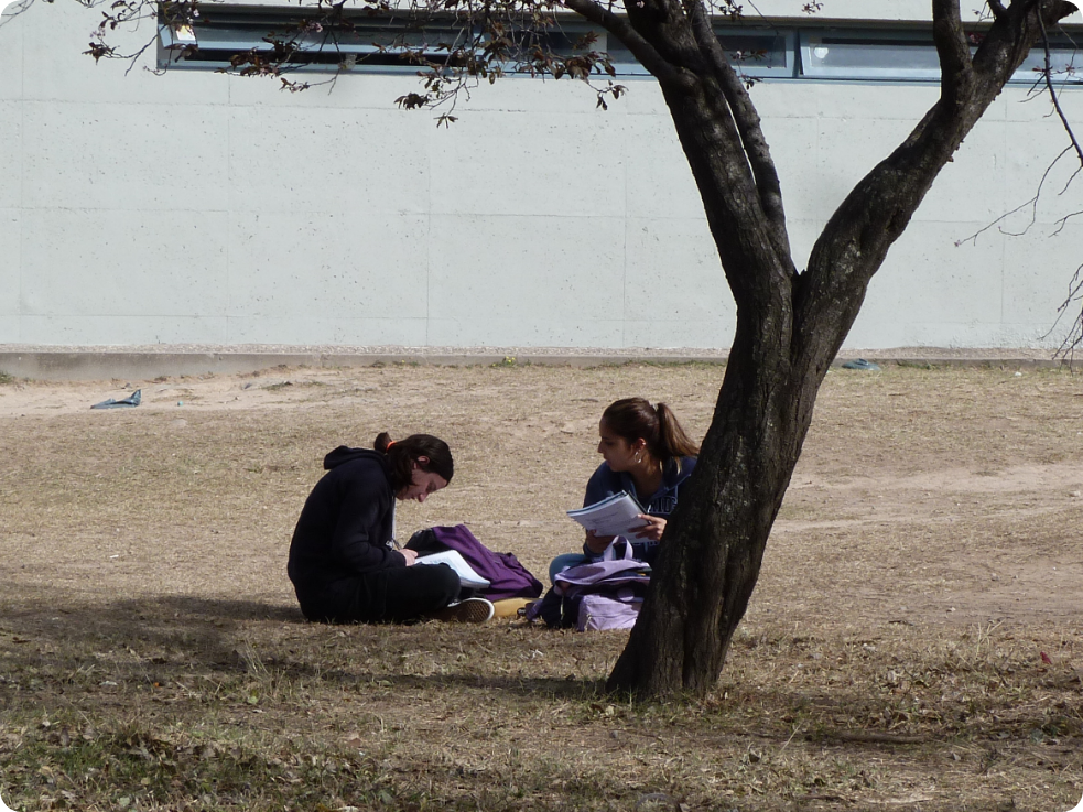 Estudiantes sentados en el piso por falta de equipamiento